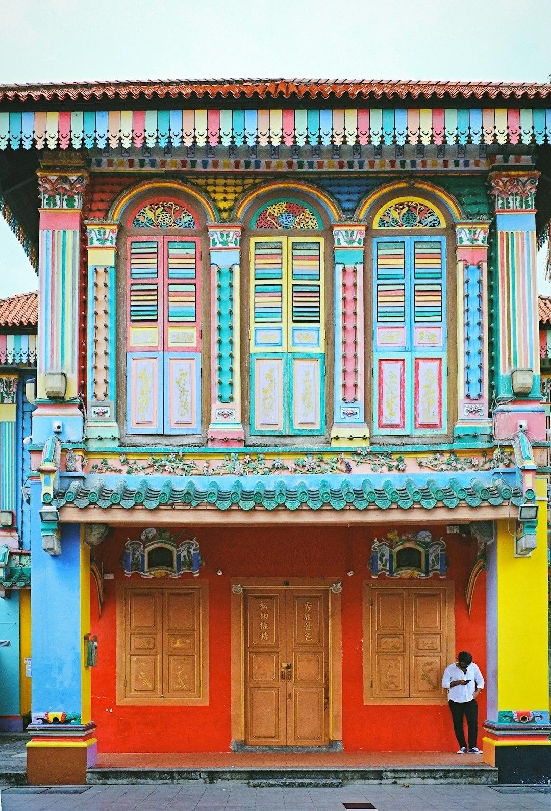 Kolorowa kamienica w stylu Peranakan z ozdobnymi oknami i detalami.