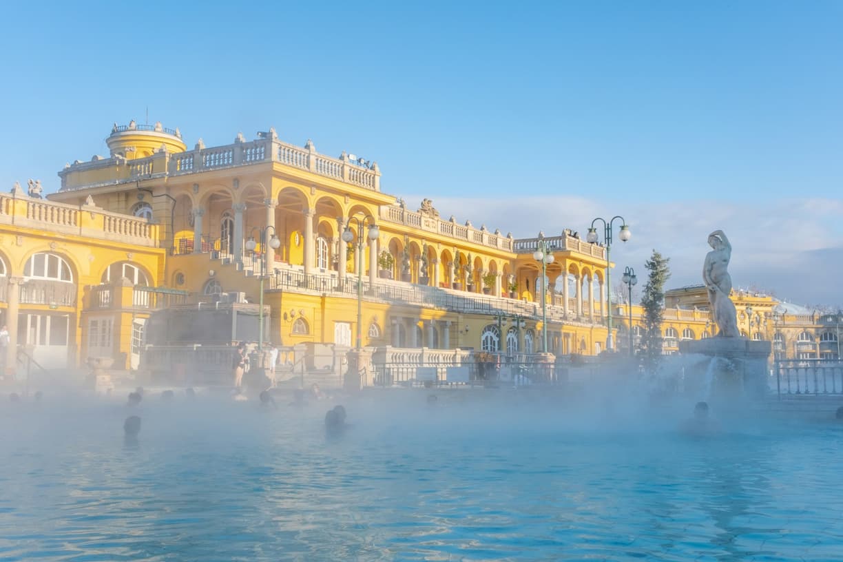 Słynne Łaźnie Szechenyi w Budapeszcie, parujący basen zewnętrzny, żółta architektura.