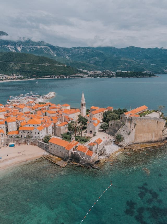 Malownicze stare miasto Budva z czerwonymi dachami, morzem i górami.