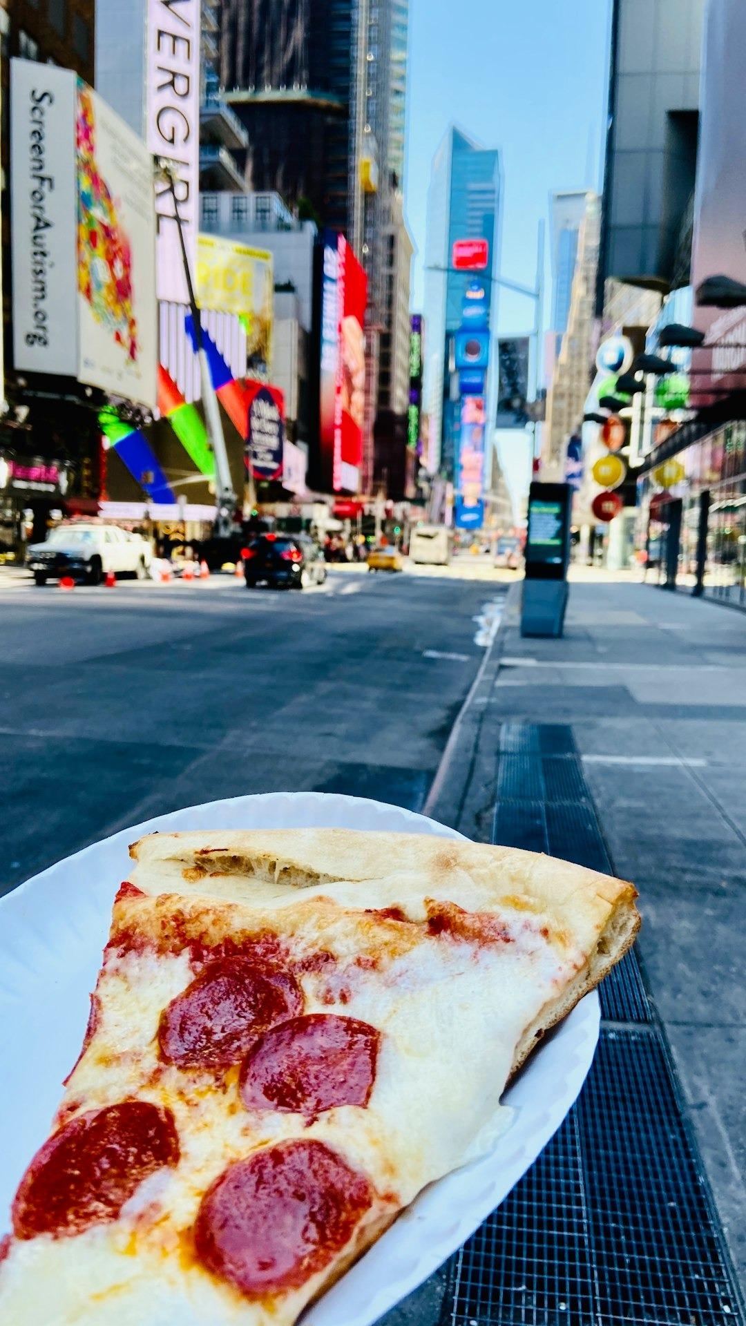 Kawałek pizzy pepperoni, Times Square Nowy Jork, jedzenie uliczne, jasny dzień.
