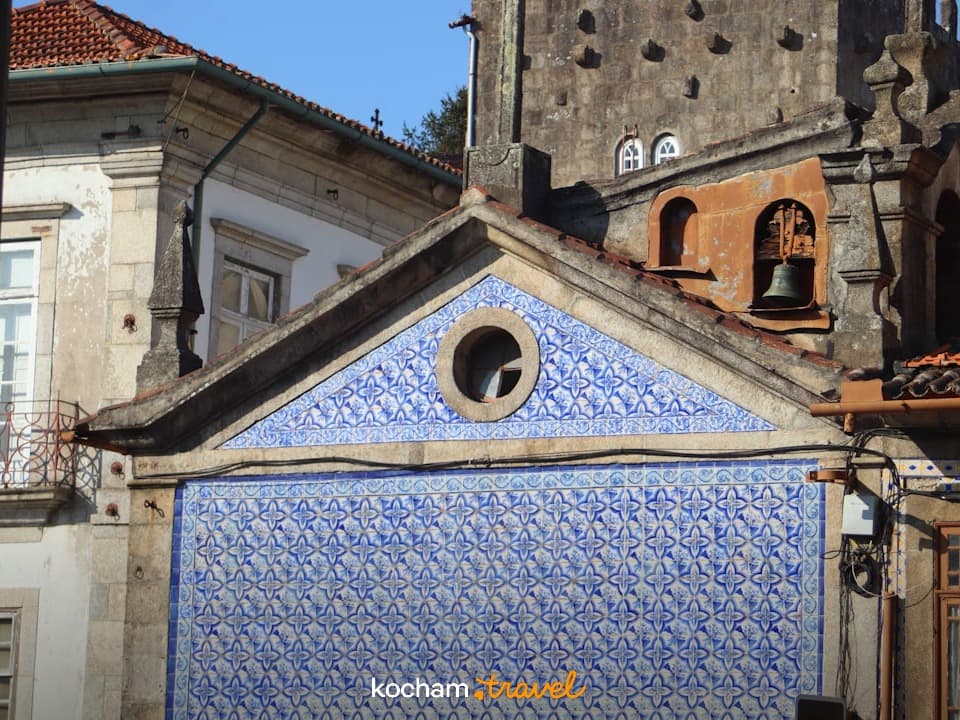 Stary budynek, niebieskie azulejos, dzwon, europejska architektura, słoneczny dzień.