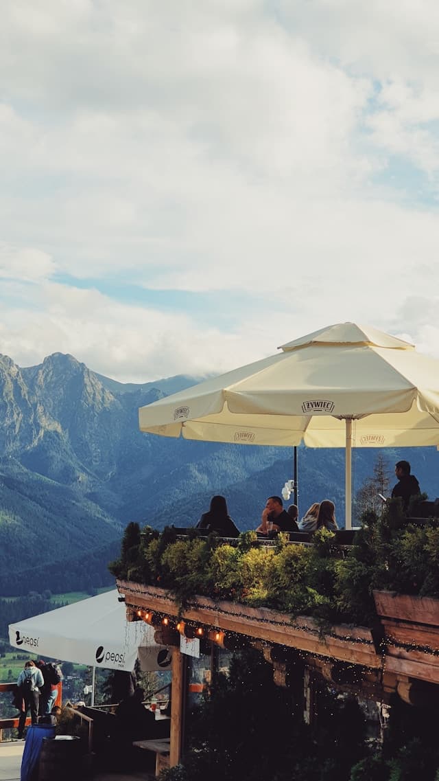 Ludzie na górskim tarasie podziwiający widok na Tatry.