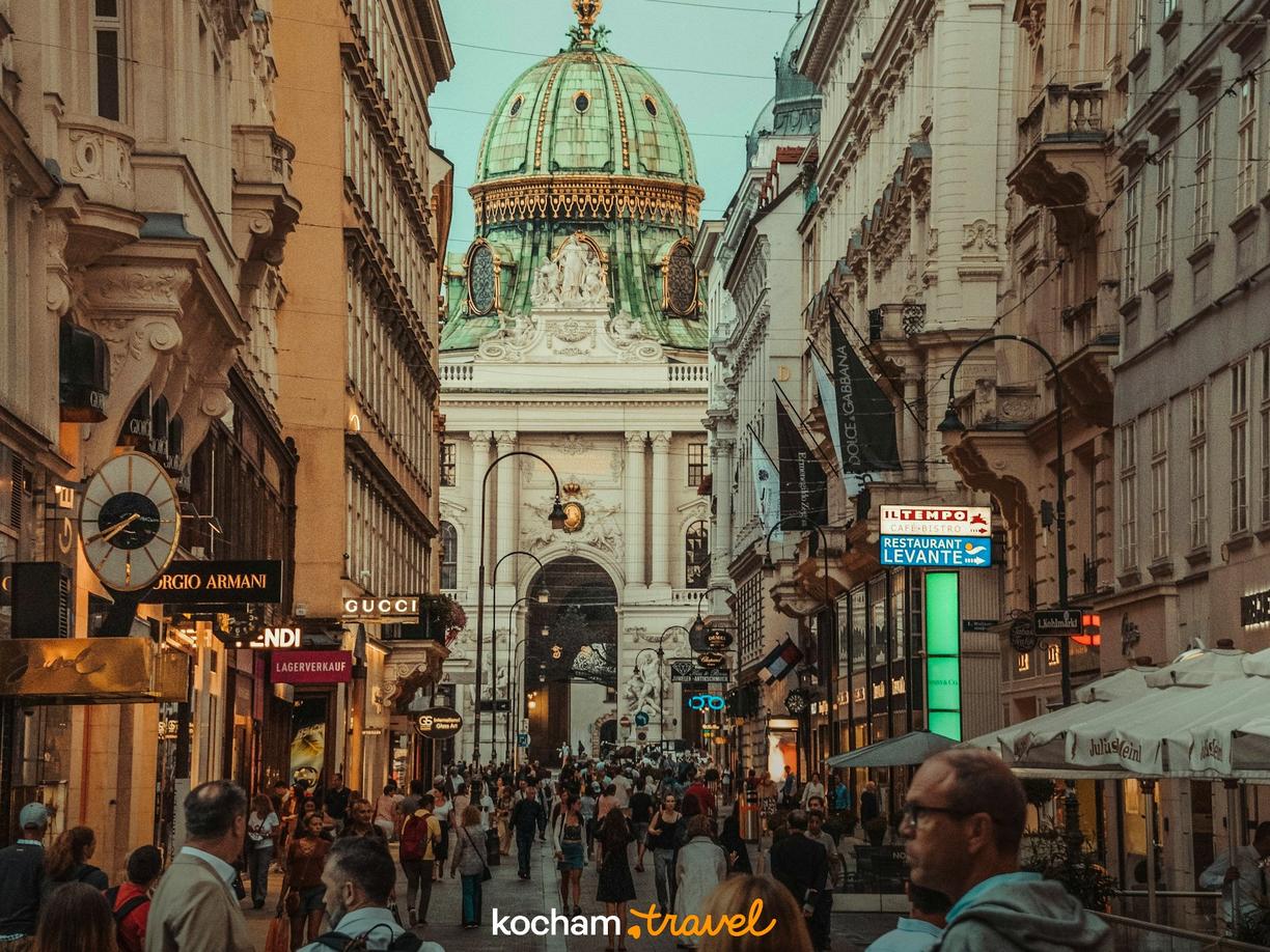 Tłoczna ulica Wiednia z zabytkową architekturą i zieloną kopułą.