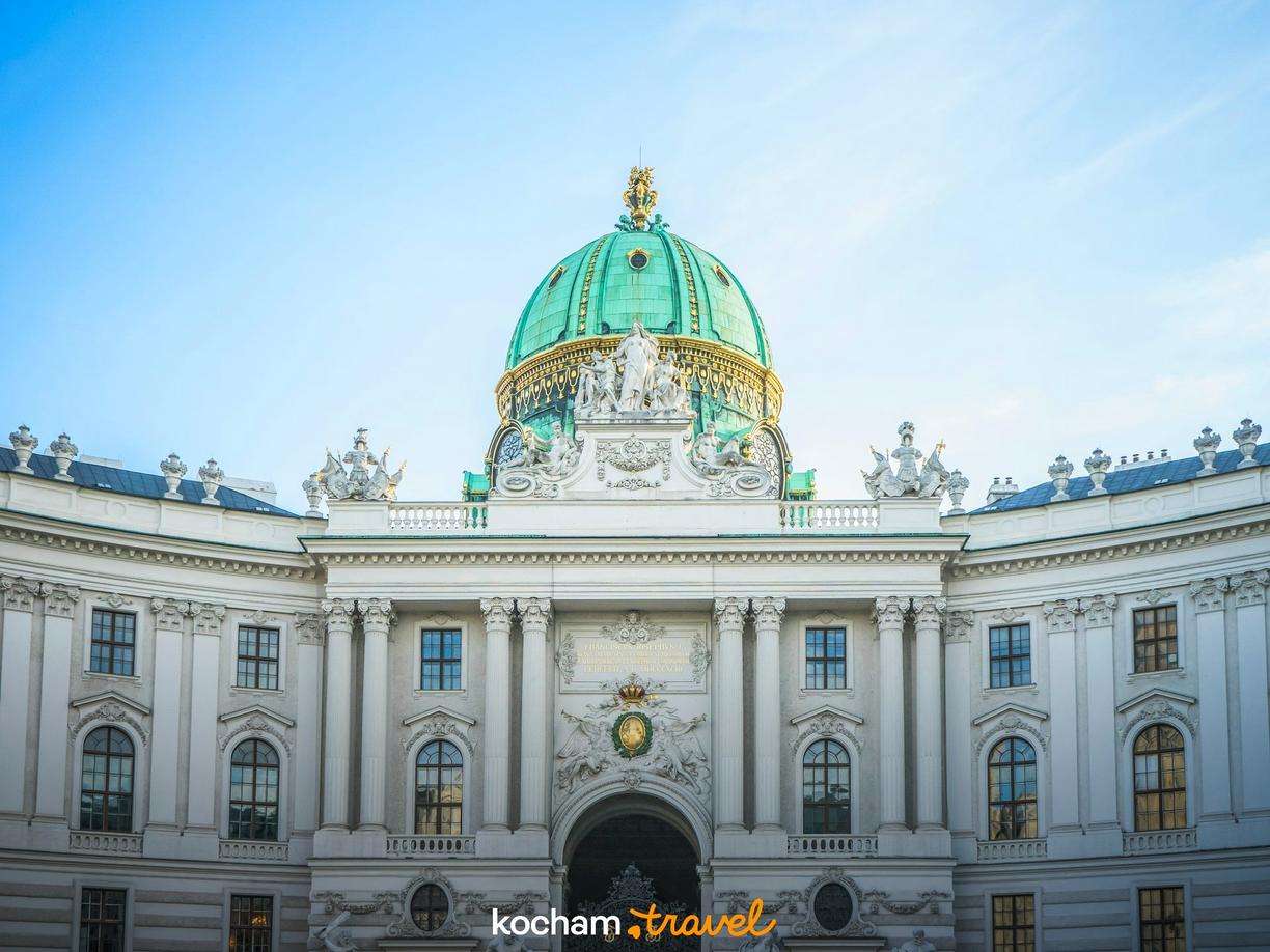 Majestatyczny Pałac Hofburg, Wiedeń, z zielono-złotą kopułą pod błękitnym niebem.