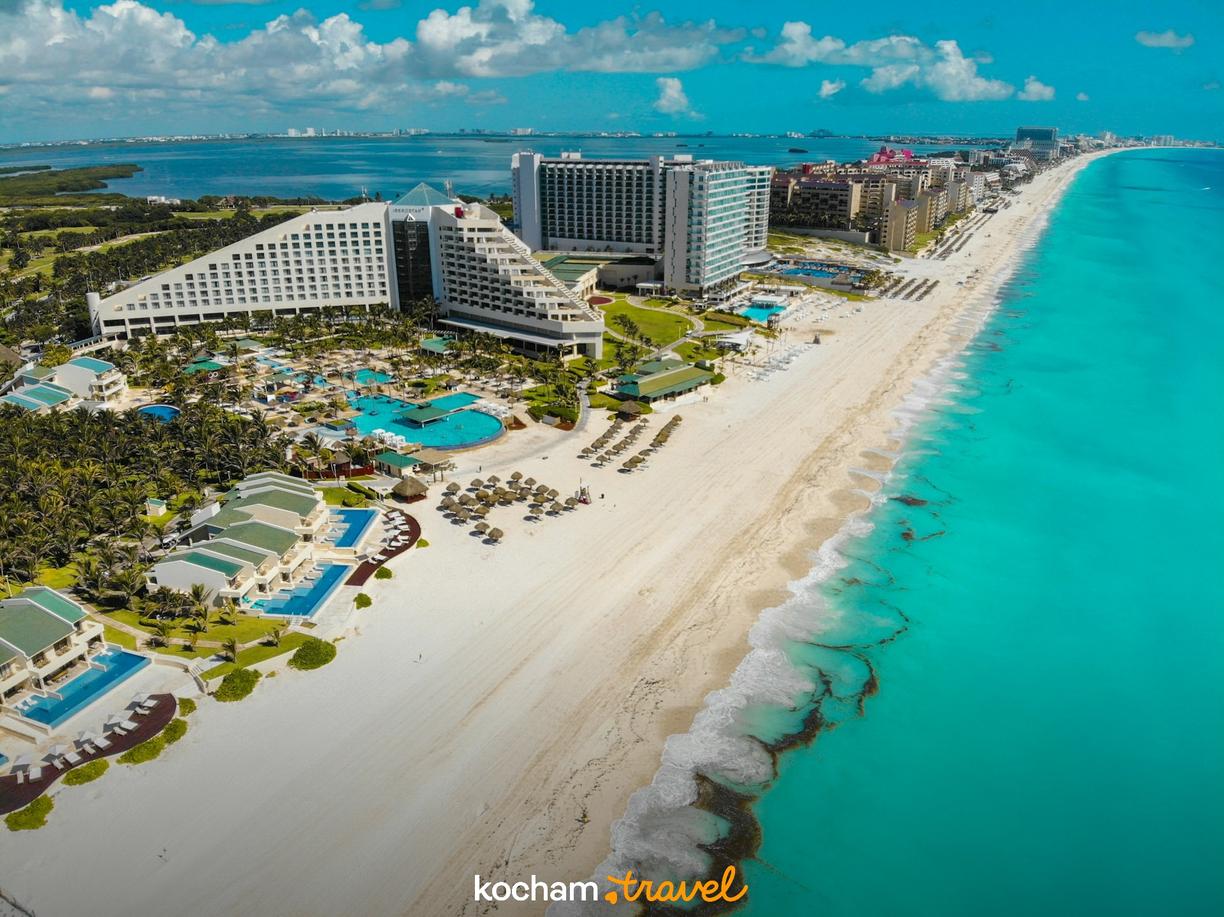 Biała plaża i turkusowy ocean przy luksusowych hotelach Cancun.