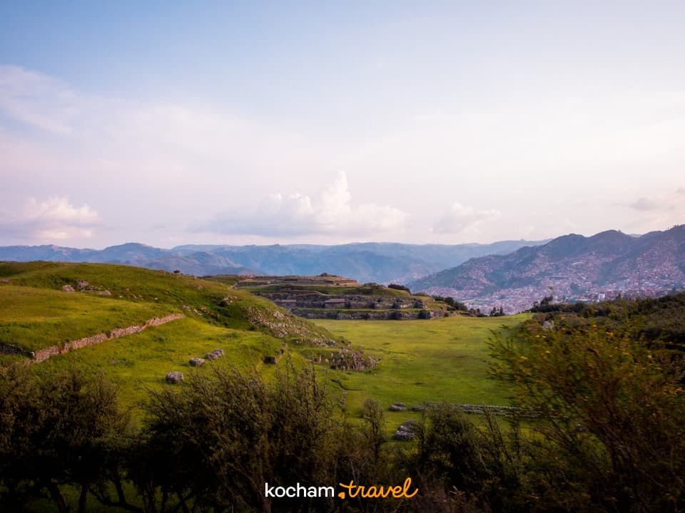 Panoramiczny widok: zielone wzgórza, inkaskie ruiny, miasto Cusco, góry.