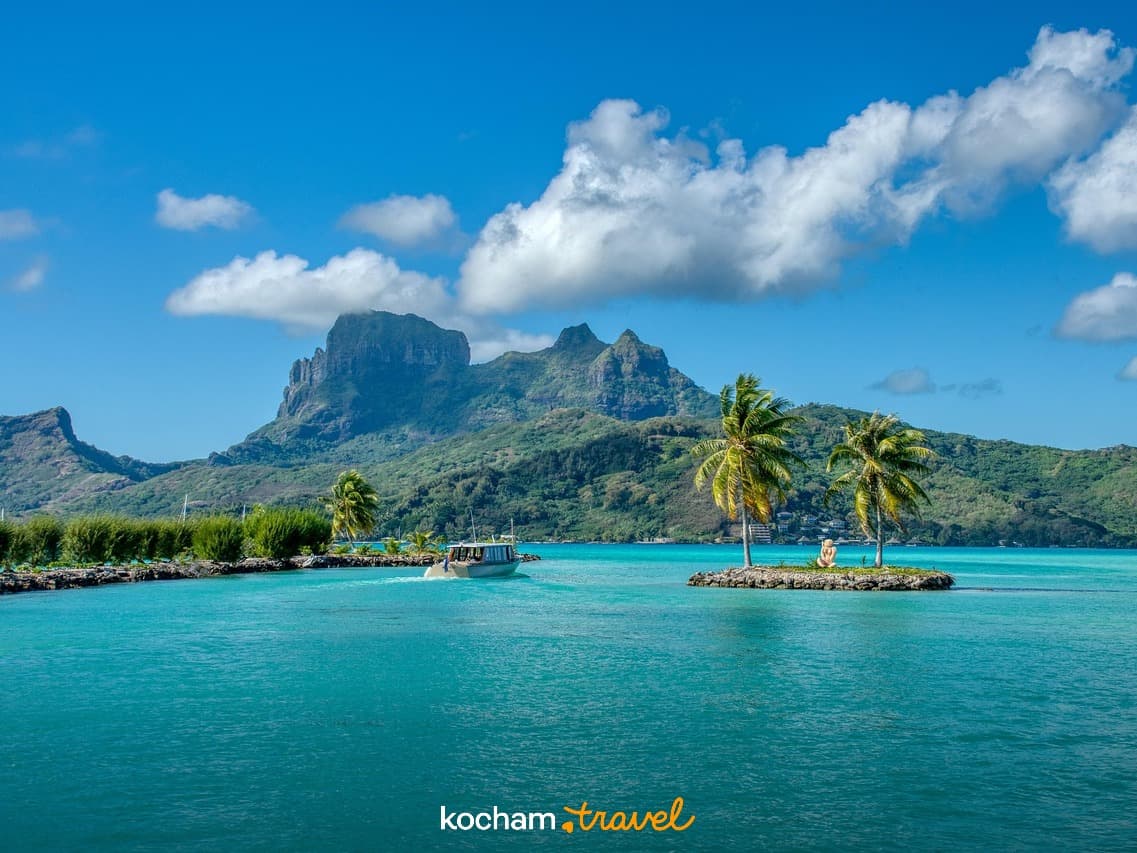 Turkusowa laguna Bora Bora, góry, łódź, palmy, tropikalny krajobraz.