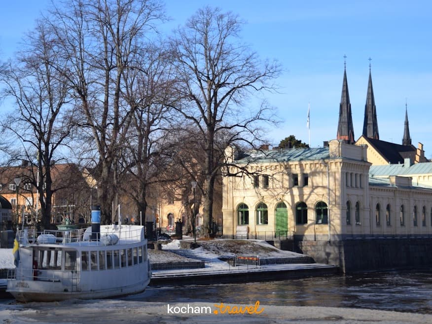 Uppsala, Szwecja: zimowa rzeka, biała łódź, zabytkowa architektura.