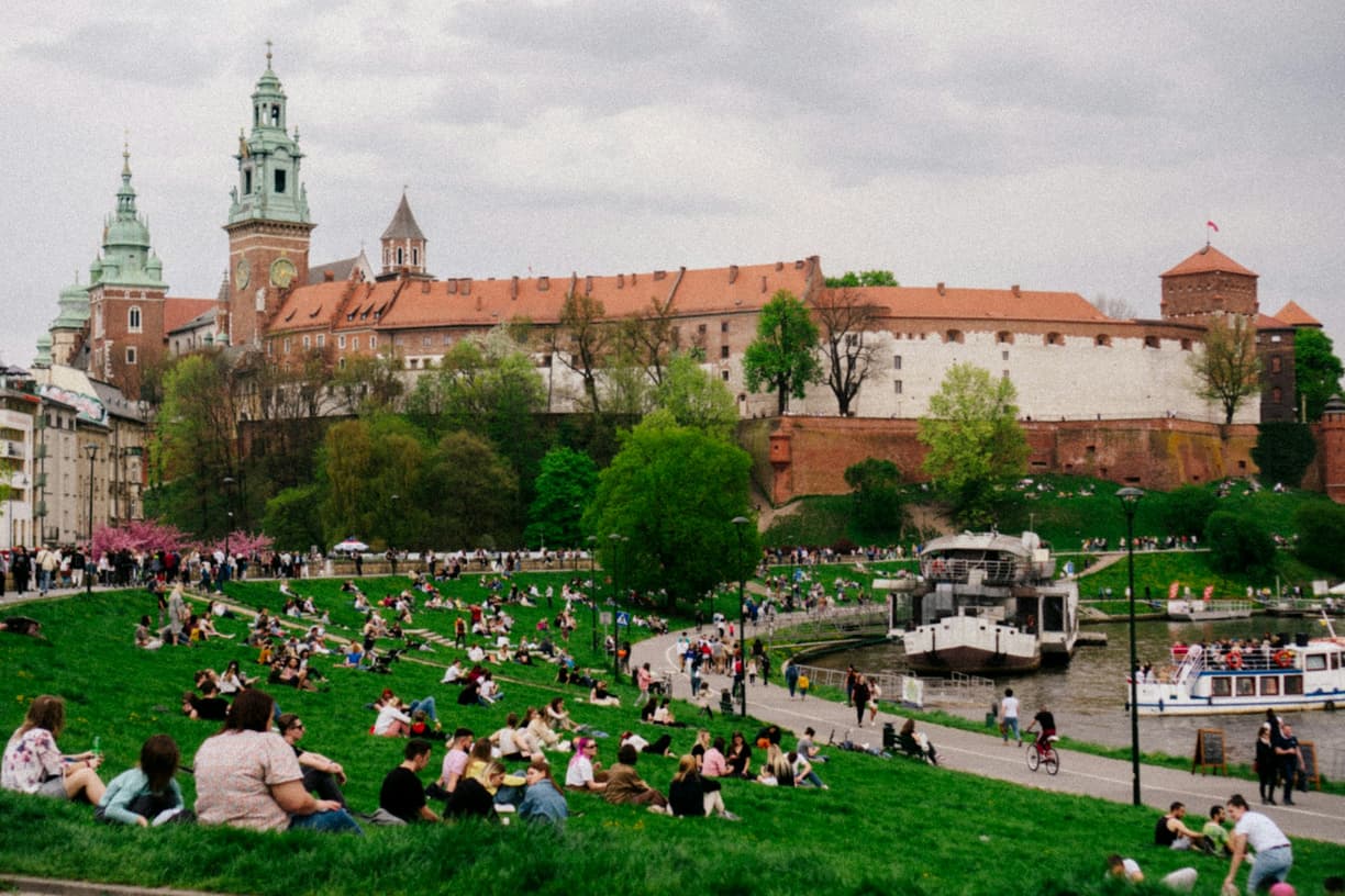 Zamek Wawelski w Krakowie, ludzie relaksujący się na trawie nad Wisłą.