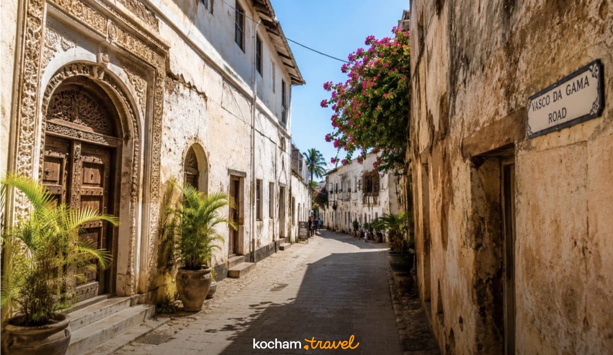 Kamienna uliczka z rzeźbionymi drzwiami i bugenwillą na Zanzibarze.