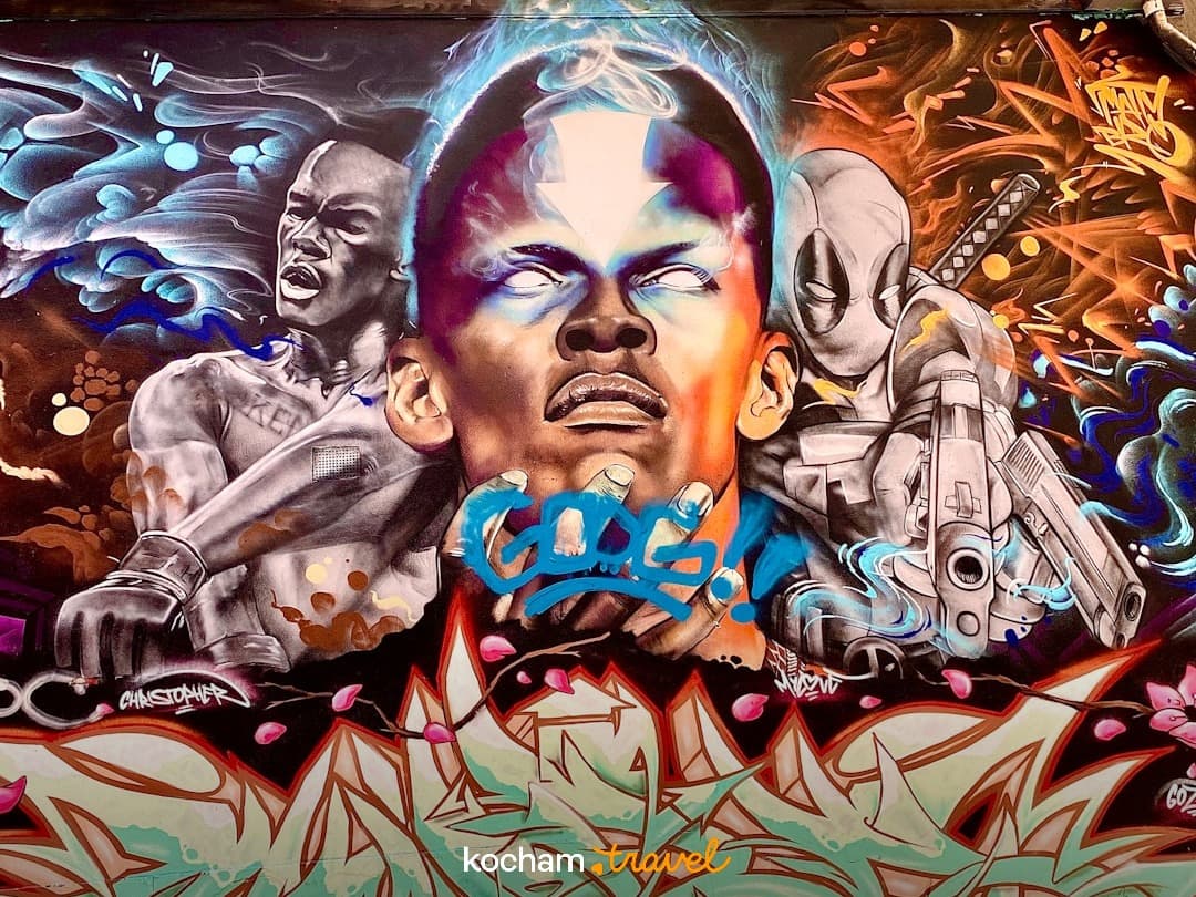 Dynamiczne graffiti mural przedstawiające postacie superbohaterów i boksera.