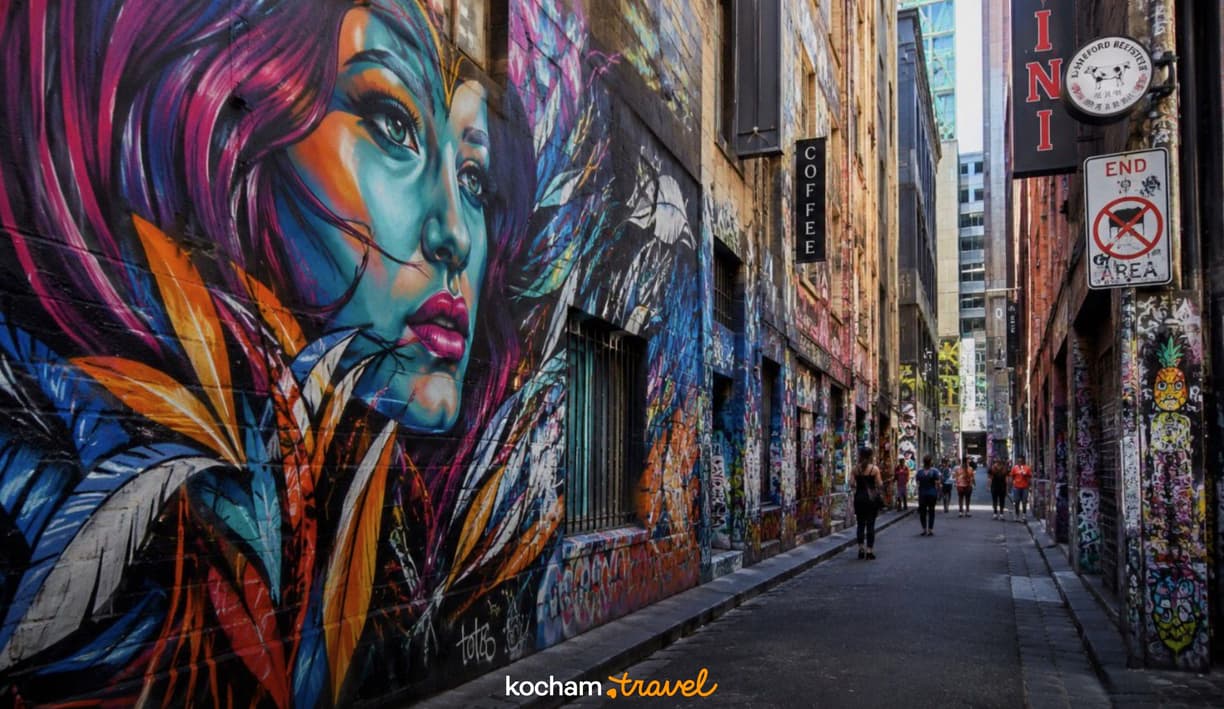Kolorowy mural kobiety i graffiti w tętniącej życiem miejskiej uliczce.