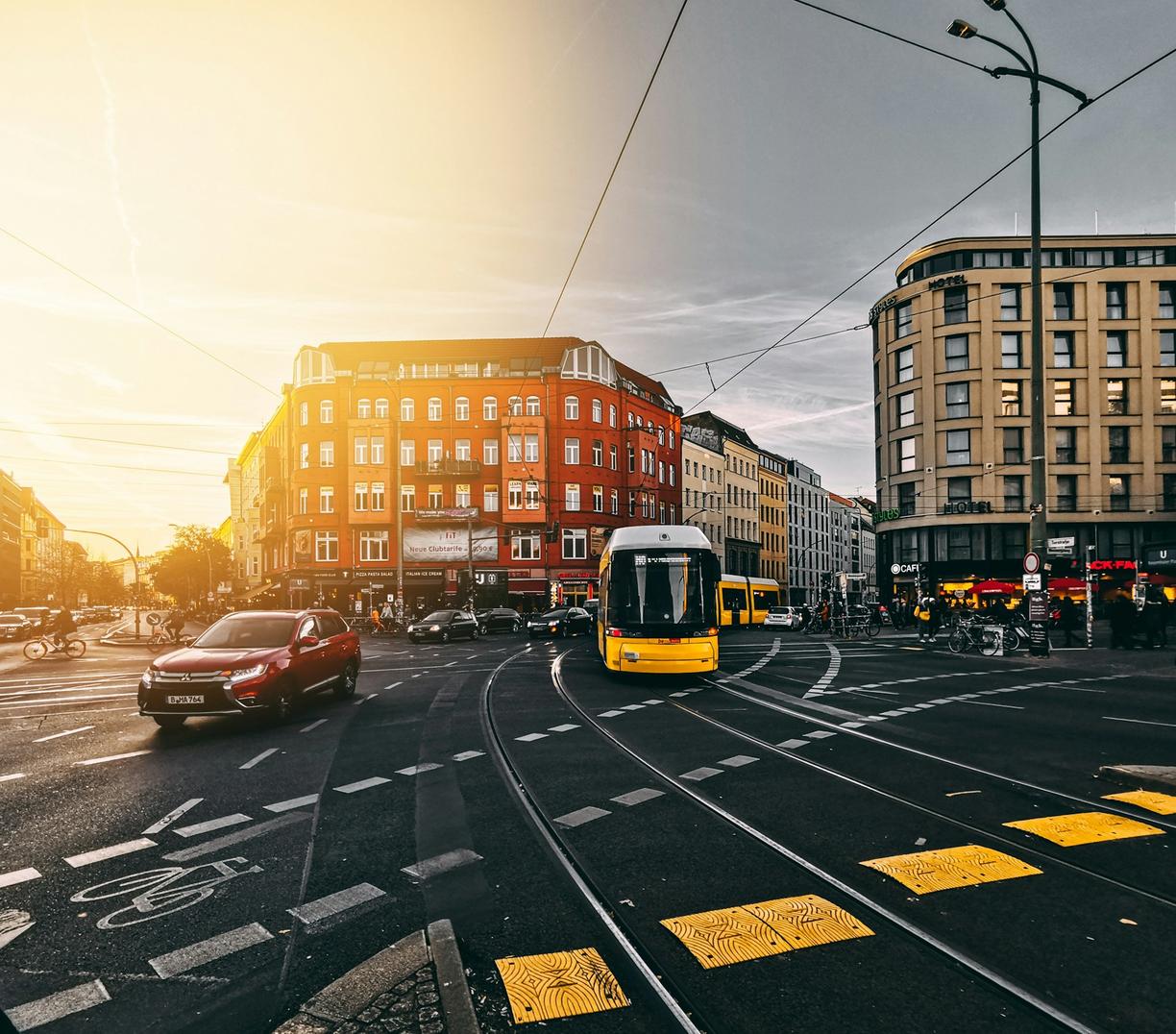 Żółty tramwaj na skrzyżowaniu w mieście o zachodzie słońca.