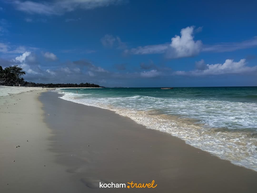 Tropikalna plaża z białym piaskiem, turkusową wodą i błękitnym niebem.