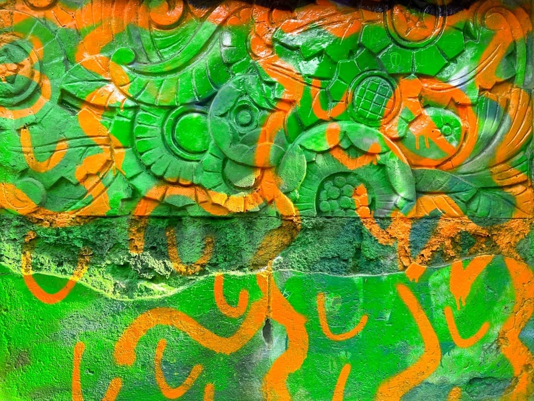 Żywe zielono-pomarańczowe graffiti na rzeźbionym detalu architektonicznym.