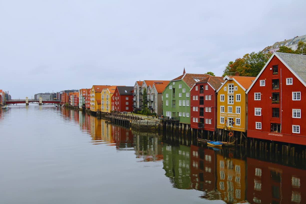 Kolorowe drewniane domy nad rzeką w Trondheim z odbiciami.
