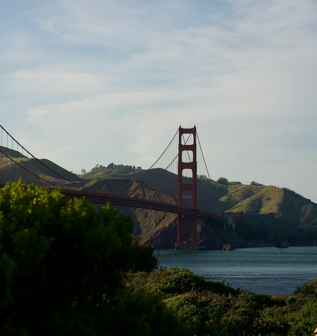 Ikoniczny Most Golden Gate, spokojna zatoka, zielone wzgórza Kalifornii.