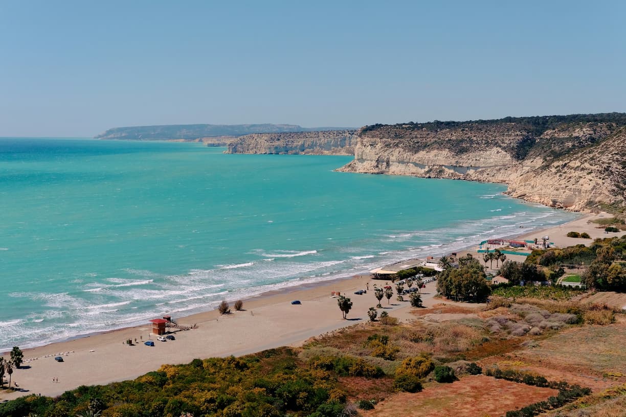 Malownicze wybrzeże z turkusową wodą, piaszczystą plażą i majestatycznymi klifami.