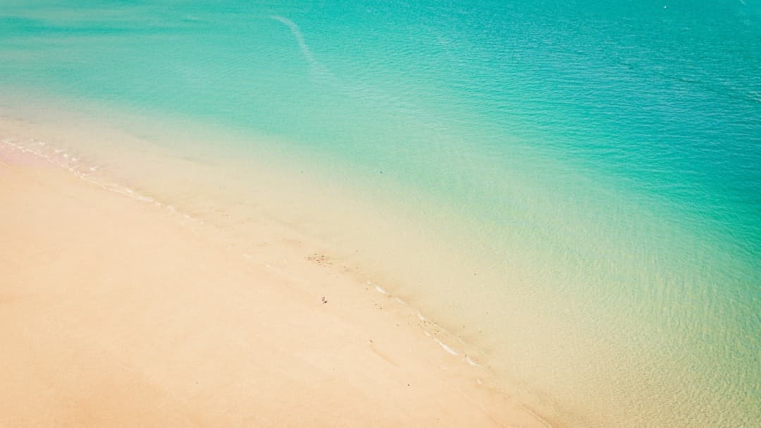 Piaszczysta plaża i krystalicznie czysta turkusowa woda z lotu ptaka.