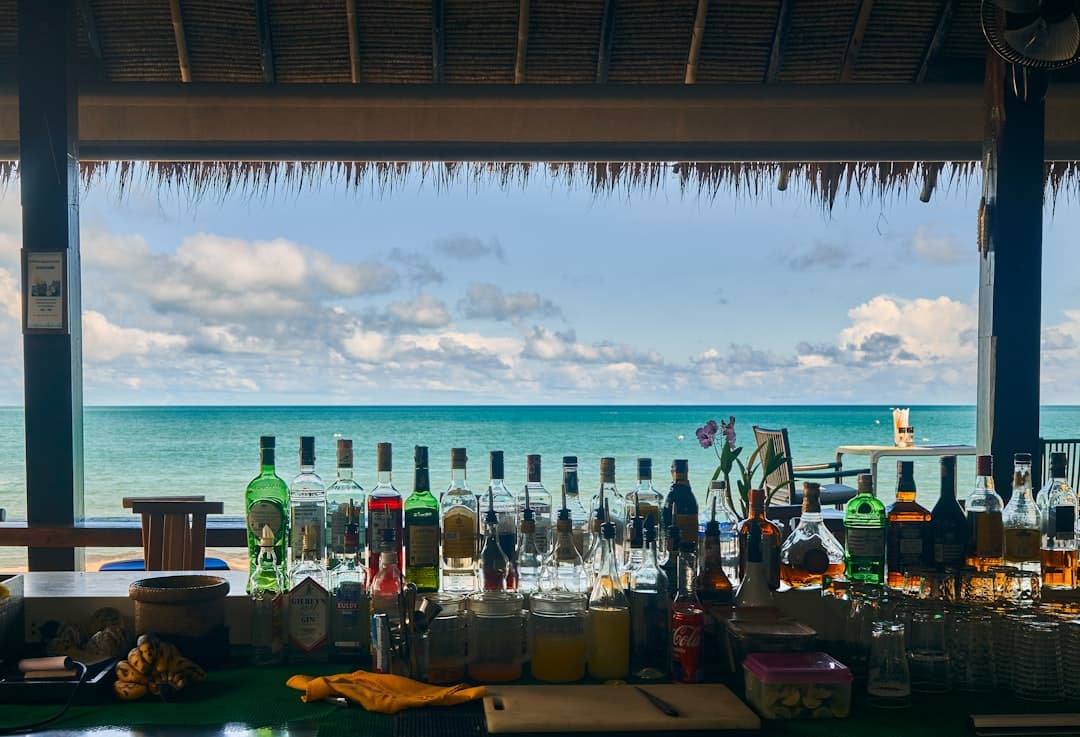 Bar z butelkami alkoholu przy oceanie, tropikalny krajobraz.