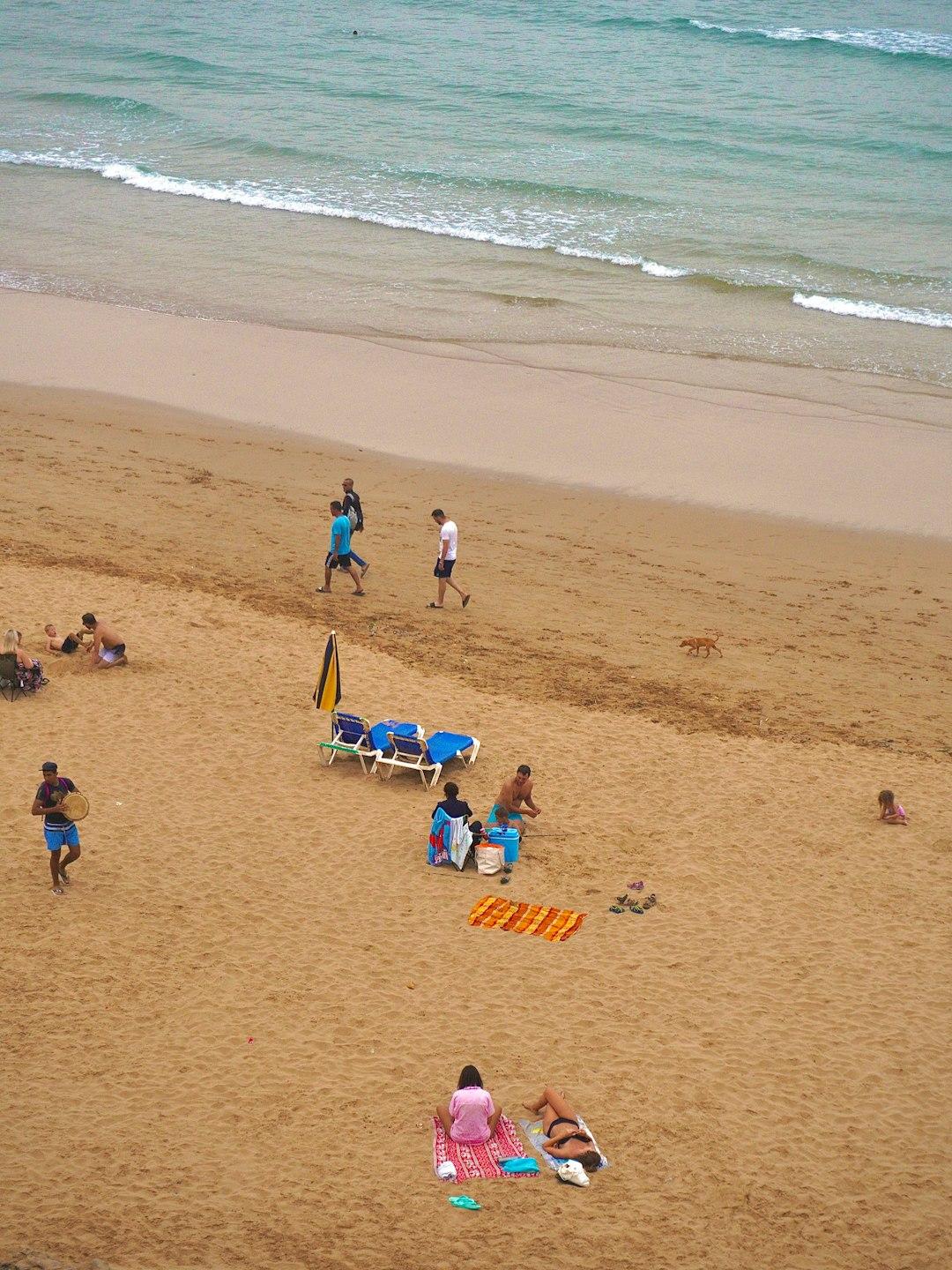 Ludzie odpoczywają na piaszczystej plaży nad morzem.