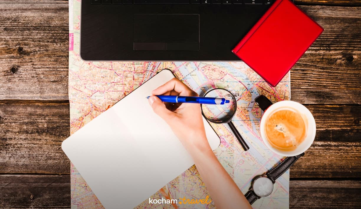 Planowanie podróży: notes, mapa, długopis, kawa i laptop.