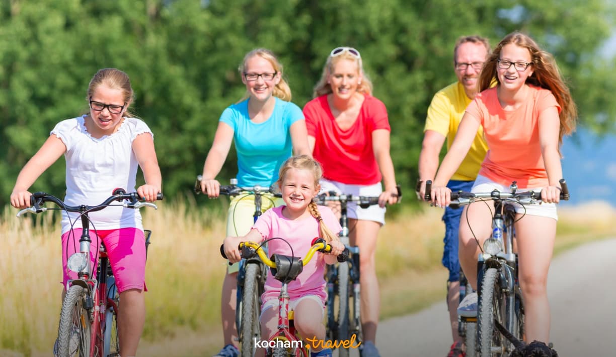 Uśmiechnięta rodzina aktywnie spędza czas na rowerach latem.